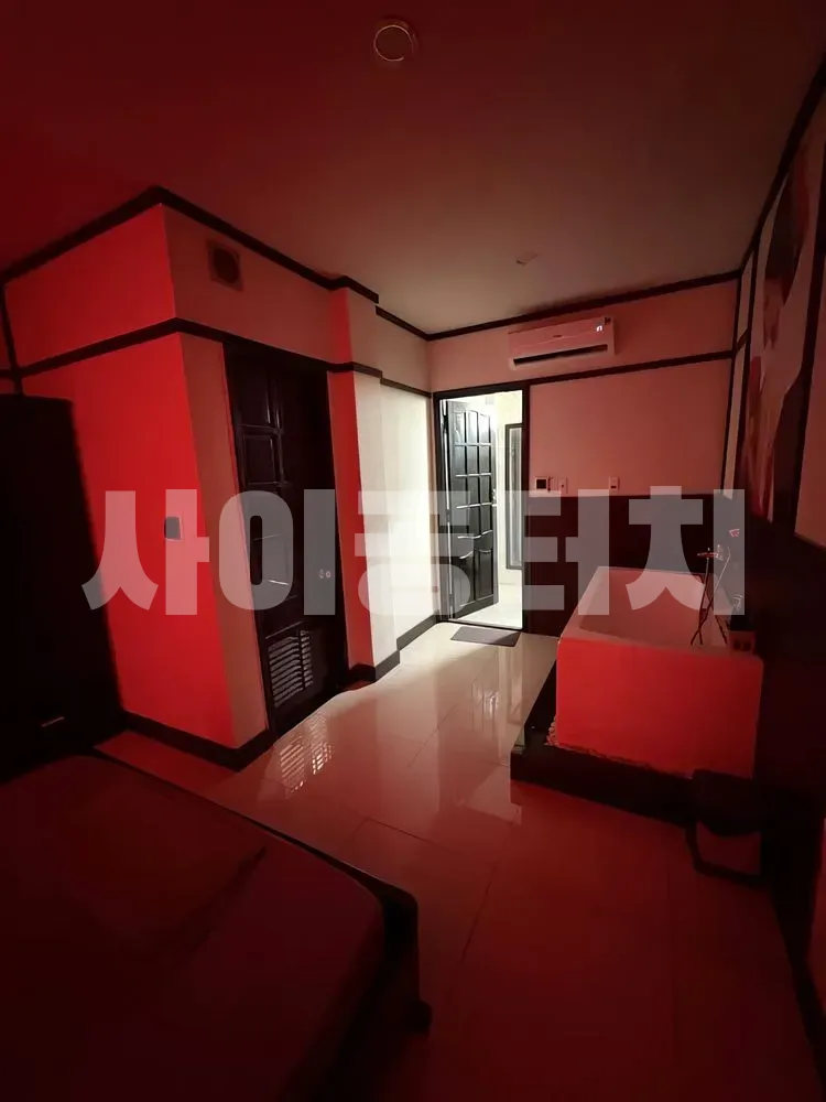 붉은 조명이 비추는 침실과 하얀 욕조